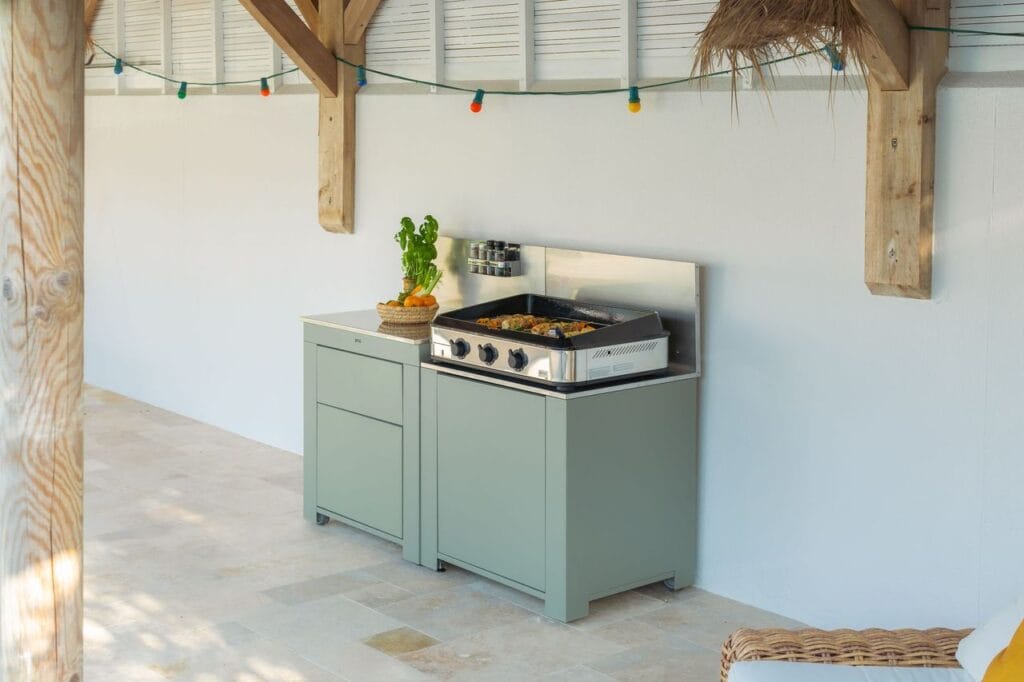 Module de cuisine extérieure mobile avec plancha posée sur un plan de travail en grès, sous une structure en bois.