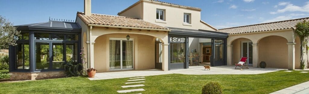 Véranda Concept Alu modèle Armonia en aluminium gris anthracite adossée à maison provençale avec jardin paysager