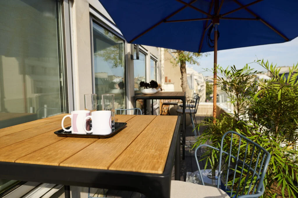 mange debout de la marque Houe, parasol bleu Tucci sur une terrasse à Paris