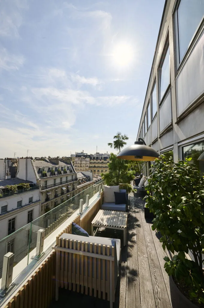 Photo d'une terrasse en bois d'une entreprise situé à Paris 8. Mobilier extérieur de chez Ego Paris, garde corps en verre, chauffage extérieur de la marque Heatsail