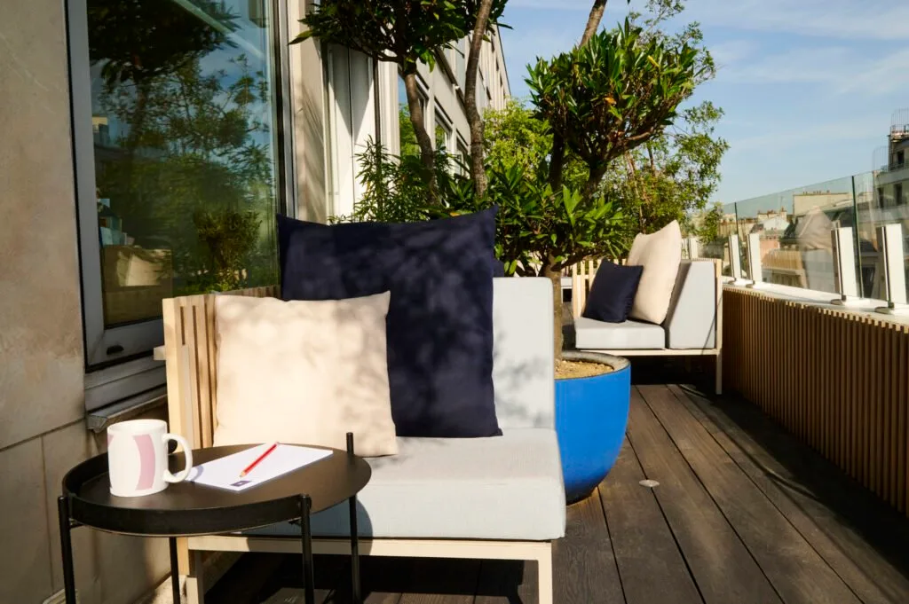 photo d'une terrasse en longueur avec mobilier extérieur et bardage Ego Paris, table basse de chez Houe et un pot bleu Domani
