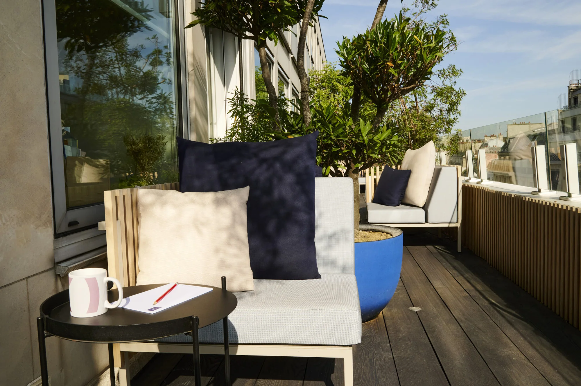 photo d'une terrasse en longueur avec mobilier extérieur et bardage Ego Paris, table basse de chez Houe et un pot bleu Domani