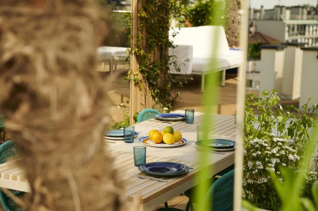Détail d'une table en bois massif et chaises artisanales dans un jardin de ville