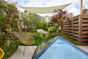 Terrasse sur mesure à Paris avec voile d'ombrage, mur végétal et vue sur les toits de zinc.