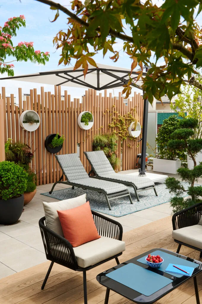 Espace détente sur terrasse avec transats, claustra en bois et végétation variée