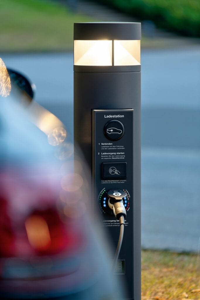 Borne lumineuse Bega avec module de recharge véhicule électrique, éclairage LED allumé en soirée avec connecteur branché et badge RFID, gris graphite