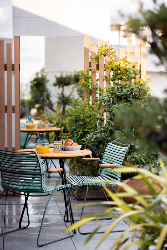 Table de petit-déjeuner dressée sur une terrasse parisienne végétalisée et entretenue